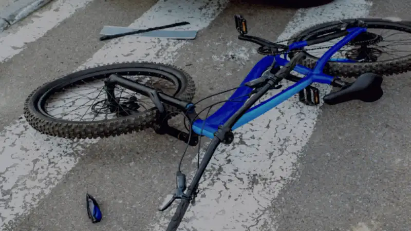 A bicycle lying on its side in a marked crosswalk after a collision