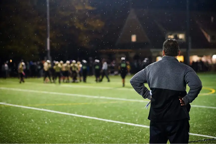 Jim Hunt watching his youth football team from the sideline during a game in the rain