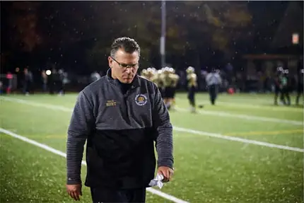 Jim Hunt walking the sideline in a team jacket during a youth football game